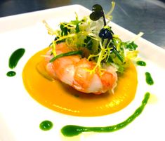 a white plate topped with food on top of a wooden table covered in green sauce