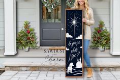 a woman holding a christmas sign in front of a house