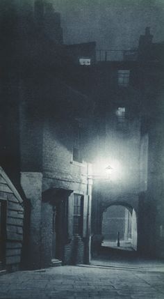 an old photo of a dark alleyway at night with the light shining on it