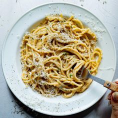 a plate of pasta with parmesan cheese on top and a wooden spoon in it