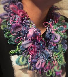 the woman is wearing a multicolored scarf with beads on it's neck