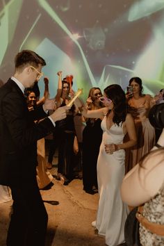 a man in a tuxedo is dancing with his friends at a formal event