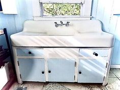 an old fashioned kitchen sink in the corner of a room with blue walls and tile flooring