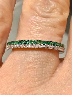 a woman's hand with a green and white diamond ring on her left finger