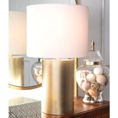 a lamp that is sitting on top of a table next to a vase with balls in it