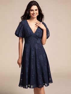 a woman in a blue dress posing for the camera with her hand on her chest