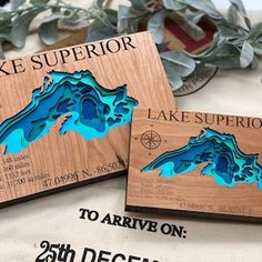 two wooden coasters with lake superior on them sitting on a table next to plants