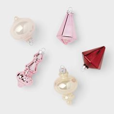 four different colored glass ornaments on a white surface with one red and one pink ornament