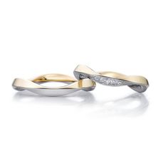 two yellow and white gold wedding rings with diamonds on each side, set against a plain background