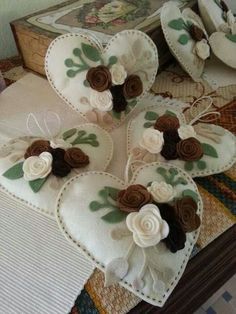 four heart shaped cushions with flowers on them sitting on a table next to a book