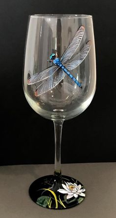 a dragonfly is sitting on top of a wine glass in front of a black background