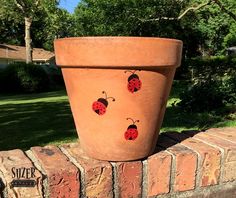 a clay pot with ladybugs painted on it sitting on top of a brick wall