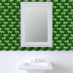 a bathroom sink sitting under a mirror in front of a green wallpapered wall