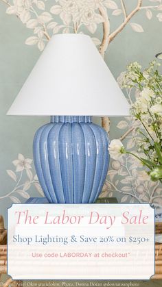 a blue lamp sitting on top of a table next to a basket with flowers in it