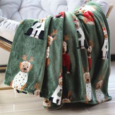 a green blanket with animals on it sitting on a chair in front of a white couch