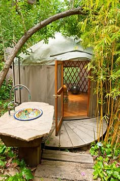 a yurt in the woods with a table and bowl on it's platform