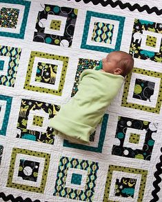 a baby laying on top of a quilt next to it's head and arms