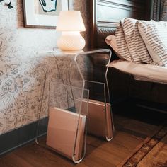 a lamp sitting on top of a glass table next to a bed in a bedroom