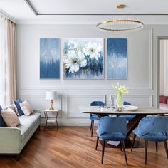 a living room filled with furniture next to a dining table and two paintings on the wall