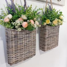 two wicker baskets with flowers in them hanging on the wall next to each other