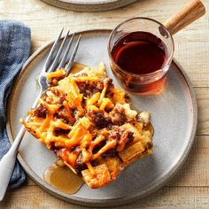 a plate with some food on it next to a fork and a glass of wine