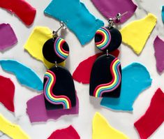 the colorful earrings are on display in front of multicolored pieces of paper that have been cut into shapes