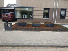 a car parked in front of a building next to a planter filled with flowers