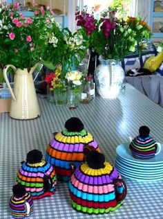 three colorful teapots sitting on top of a table next to vases with flowers in them