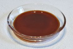 a glass bowl filled with brown liquid on top of a white table