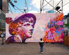 a person standing in front of a large mural