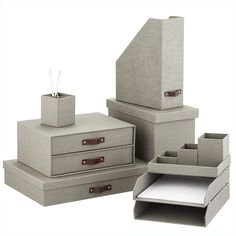 three boxes with drawers are stacked on top of each other and one has a pen in it