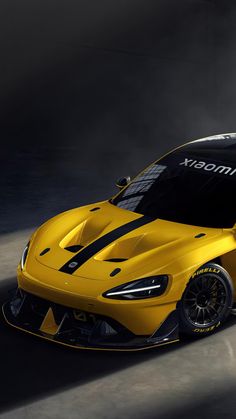 a yellow sports car with black stripes on the front and side, in a dark room