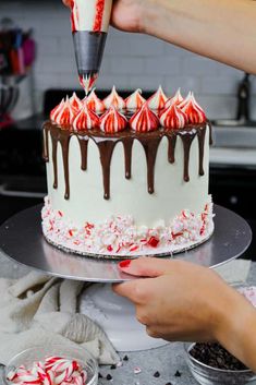 someone decorating a cake with chocolate and candy canes