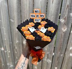 someone holding up a bouquet of flowers with ghost decorations on it and the words will you be my boo?