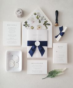 the wedding stationery is laid out on top of each other, including an envelope with a blue ribbon