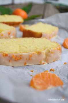 slices of cake sitting on top of white paper next to oranges and green leaves