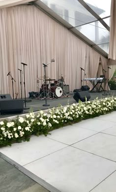 the stage is set up for an event with white flowers and microphones on it