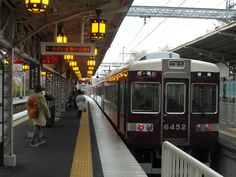 people are waiting for the train to arrive at the station in japan, with lights on either side