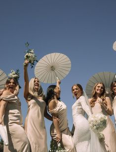 a group of bridesmaids holding umbrellas in the air