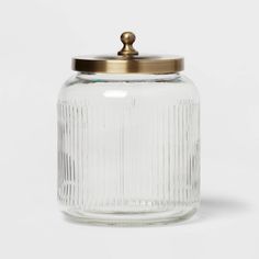 an empty glass jar with a brass lid on a white background, it appears to be used as a storage container