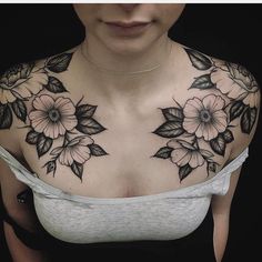 a woman's chest with flowers and leaves tattooed on her upper half - arm