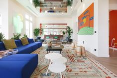 a living room filled with blue couches and colorful paintings on the wall above them