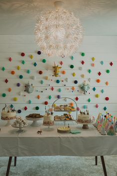 a table topped with lots of cake and cupcakes next to a chandelier