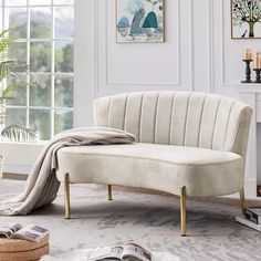 a white couch sitting next to a window on top of a carpeted floor in front of a fireplace