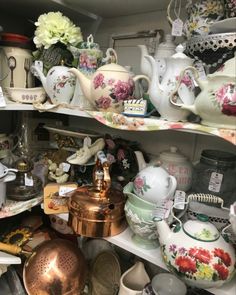 a shelf filled with lots of different types of tea pots and saucers on top of each other