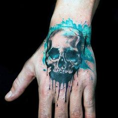 a man's hand with a skull and watercolor splatters on it