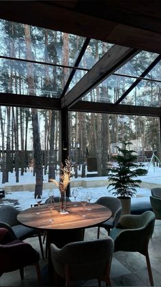 a dining room table and chairs in front of a large window with snow on the ground