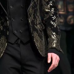 a man in a black suit and gold jacket