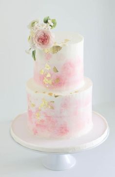 a three tiered cake with pink and white flowers on the top is sitting on a plate