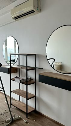 an empty room with two round mirrors on the wall and a shelf in front of it